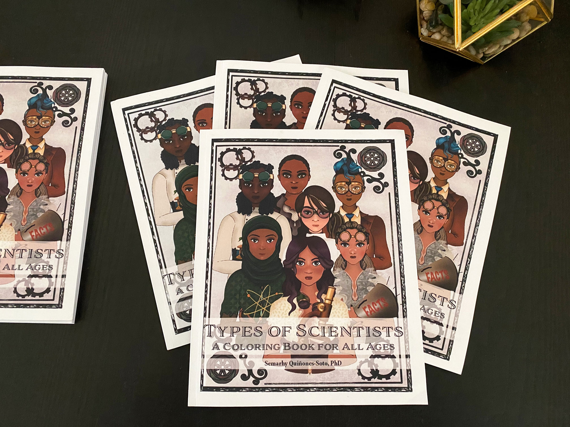 Copies of the coloring book "科学家的类型" sit on a black background